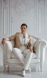 a beautiful woman in all white sitting on a white couch