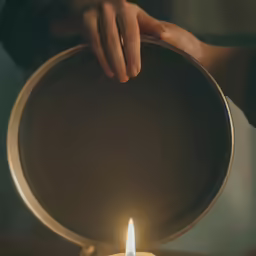 a person holding a pan with a lit candle inside