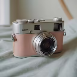 an old silver and pink camera on a blanket