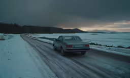 a white car drives down the snowy road