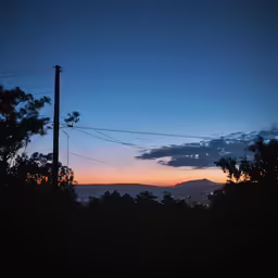 the sun is setting behind a telephone pole and wire