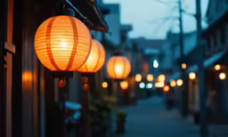 a long row of lanterns hang from the side of buildings
