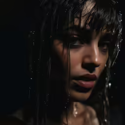 a woman with rain on her face looks out into the distance