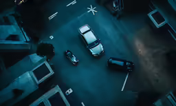 an aerial view of three black cars parked on the street