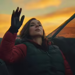the woman is wearing a down jacket and flying her kite