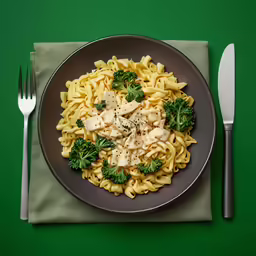a plate filled with pasta topped with chicken and broccoli
