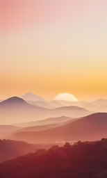 a hazy sunrise with a mountain valley and mountains in the background