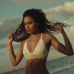 a woman in white top standing by the ocean