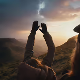 a person stands on top of a mountain above the hills and raises their hands up