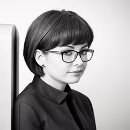 a girl wearing glasses looking over a computer screen