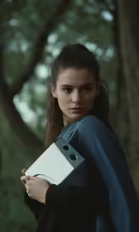 a woman holding a folder with trees in the background