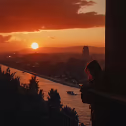a woman stands overlooking the city and watches the sun set