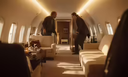 two people standing inside a small airplane with white couches