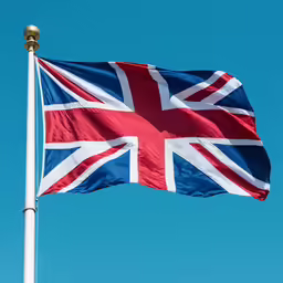 a flag of the united kingdom flies in a blue sky