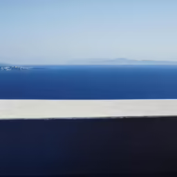 a man sitting on a ledge looking out at the water