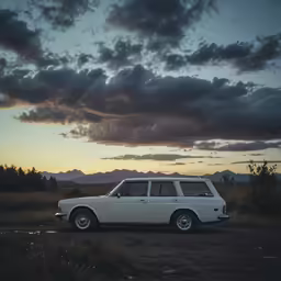 the sun sets behind an old car in a field