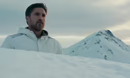 a man sitting in the snow looking towards the camera