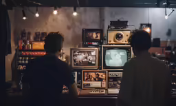 two people watching a television set with multiple screen displays