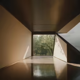 the corner of a room with a glass window and wooden floor