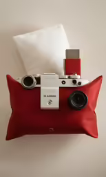 a camera laying on a red pillow and blanket