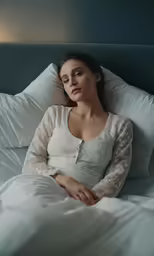 a woman laying in bed with her hands on her back