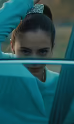 young woman with dark eyes and tiara getting out of a car