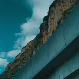 the side of a concrete wall with mountains in the background