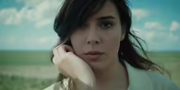 a beautiful young woman in a white shirt holding her hand to her face
