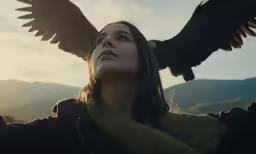 a woman in a jacket holds out her hand while a bird perches on her arm