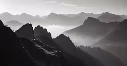 black and white photo of mountains in the fog
