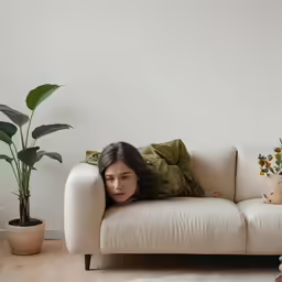 a girl laying down on a white couch with a green pillow