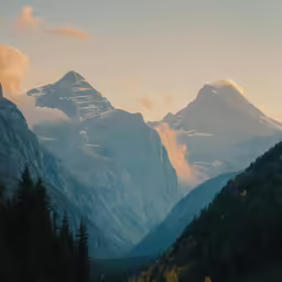 the sun rises behind the mountains as seen from the valley below