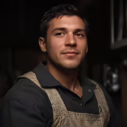 man in black shirt in an oven looking off into the distance