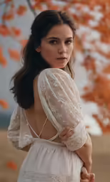 a woman in a white dress stands in front of a tree