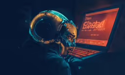 a person in dark with a headphones on using a laptop