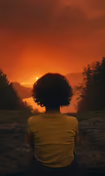 a person that is sitting and looking at the sunset