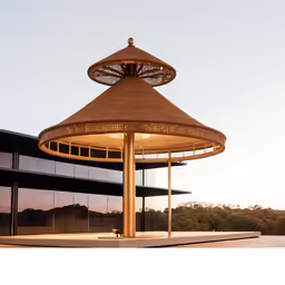 a very tall brown structure near a building