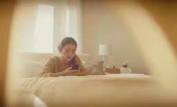 a lady in the bed playing with her cell phone