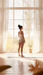 a young woman is standing in front of a window and looking out of it