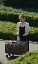 a woman walking down the street pulling a large piece of luggage