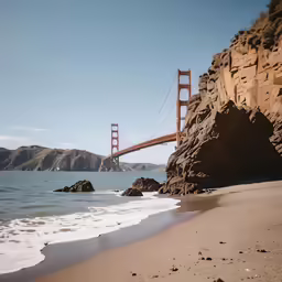a golden gate bridge spanning the width of the ocean from the beach