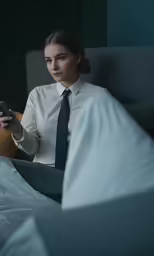 a woman is sitting on a bed holding a cell phone