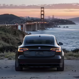 a black car parked on the side of a road near the ocean