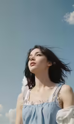 the young asian woman is standing under a blue sky
