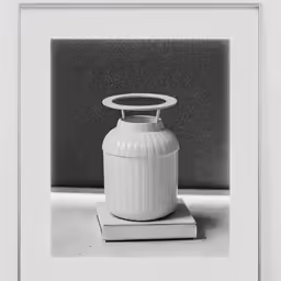 a white vase with an odd head sitting on some books