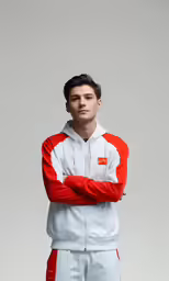 a man standing in a red and white jacket with his arms folded