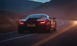 a red sports car driving on the highway with a rear brake light on