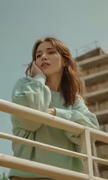 a woman with her arms crossed stands by a rail