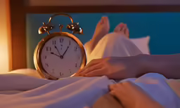 a person laying in bed with their feet on the nightstand
