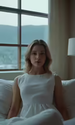 a woman in a white dress sitting on a bed